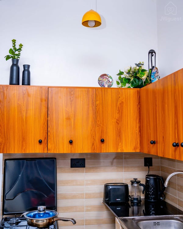 Kitchen - furnished with a kettle, coffee maker, toaster, stove, fridge and sink. You also have cupboards at your… — Cozy 2-Bedroom Haven Near KGL Airport - Valley View, Kigali, Kigali City