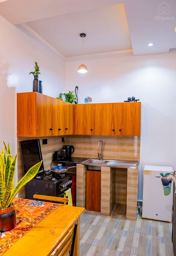 Kitchen - furnished with a kettle, coffee maker, toaster, stove, fridge and sink. You also have cupboards at your… — Cozy 2-Bedroom Haven Near KGL Airport - Valley View, Kigali, Kigali City